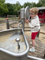 Boy playing with water and sand at Battersea Park Zoo